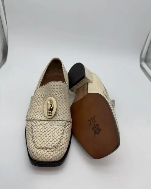 A pair of cream perforated loafers, one turned over to show its new leather sole