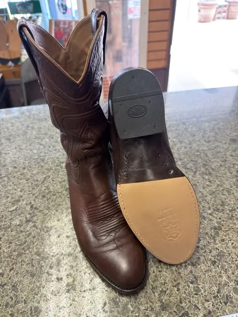A brown cowboy boot standing beside its new tan leather sole