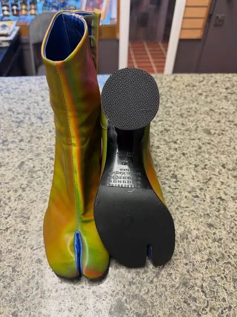 An iridescent Tabi boot beside the black split-toe sole fitted to it