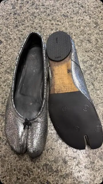 A silver split-toe Tabi flat beside its new black rubber sole