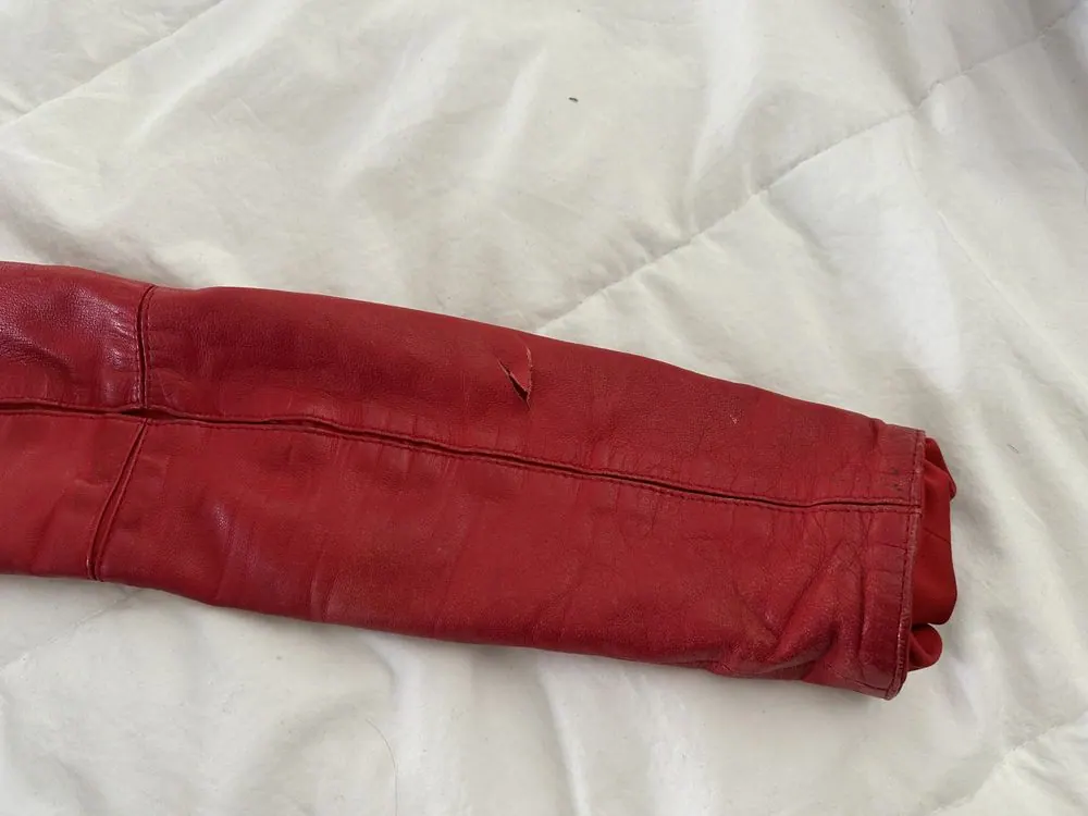 A gash in a red leather sleeve, sewn closed