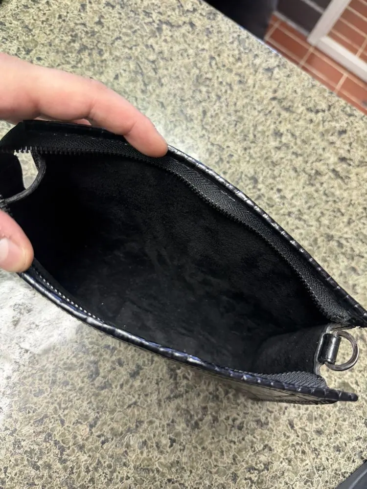 A black leather clutch opened up at the counter for a zipper repair
