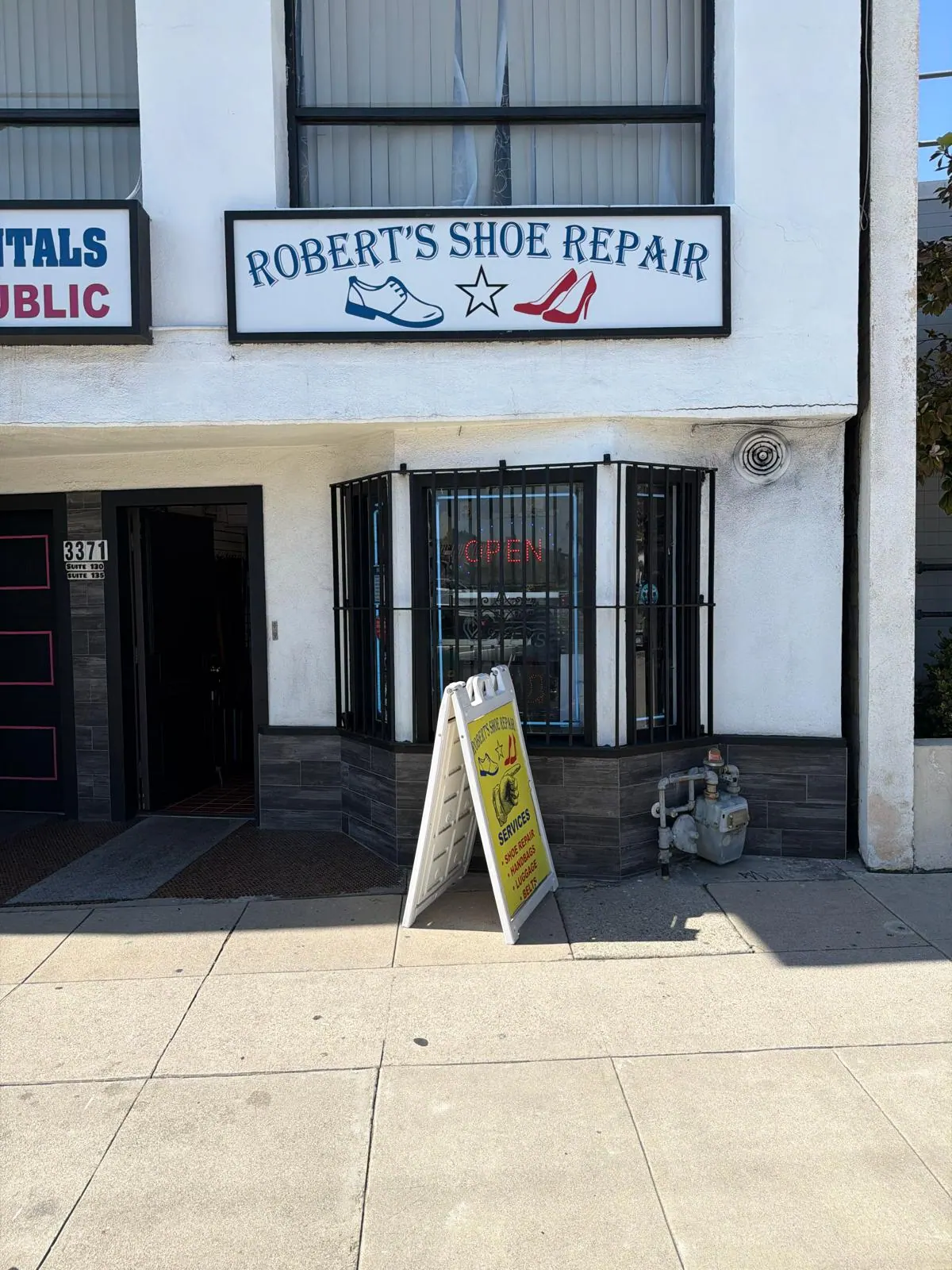 The Robert's Shoe Repair storefront at 3371 Glendale Blvd: the sign above the bay window, the OPEN sign lit, and the yellow services board out on the sidewalk